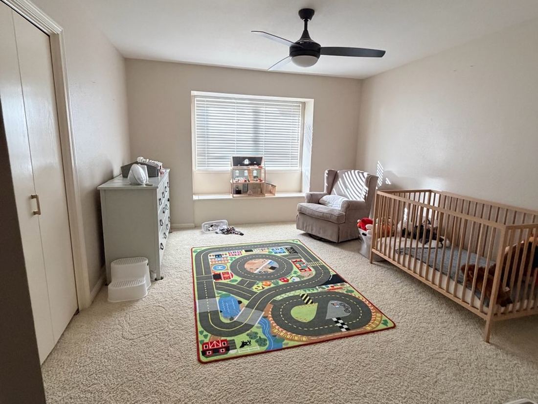 Children's room with car-track play rug, crib, glider and dresser